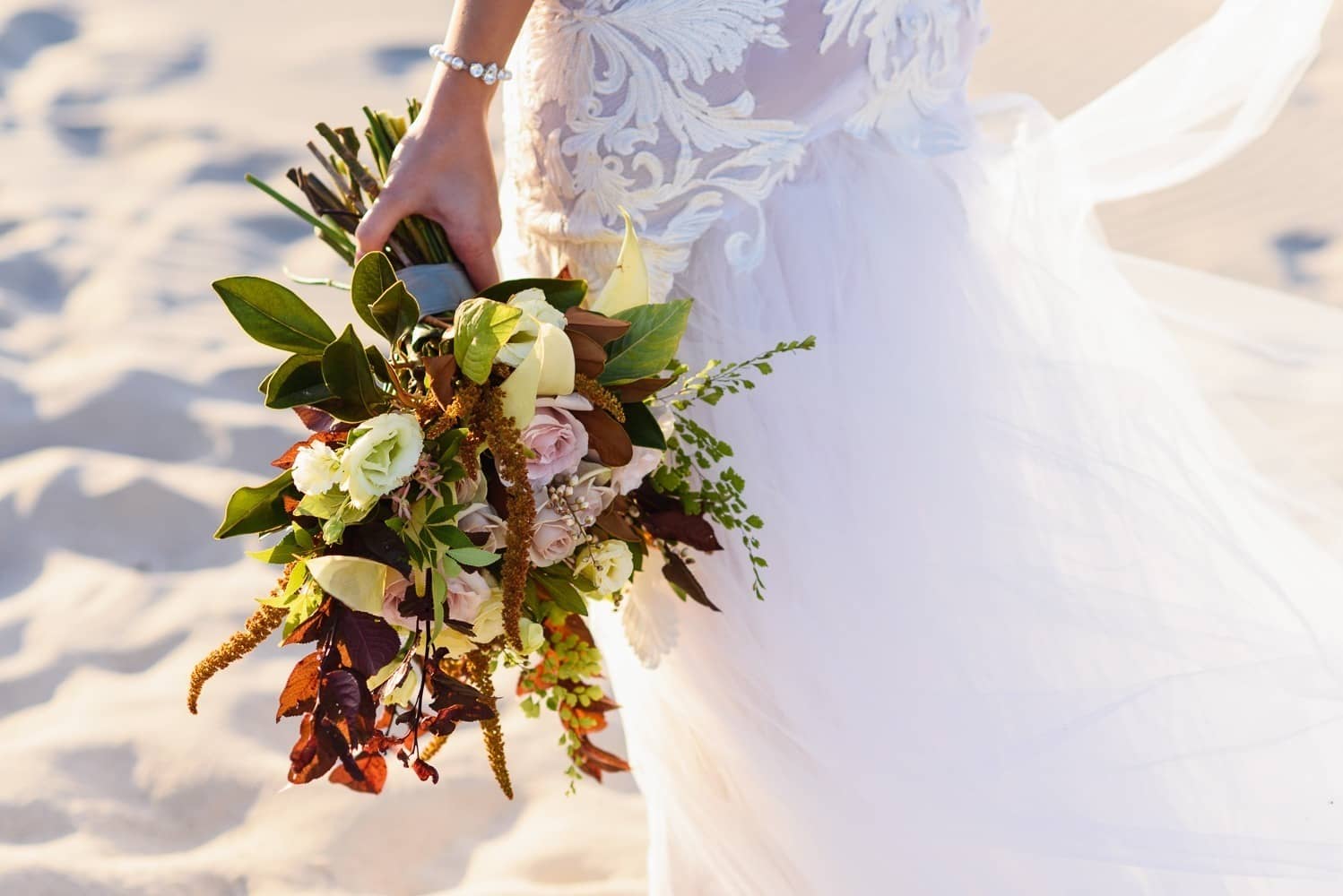 Perth Wedding Florist. A bridal bouquet held by bride on beach.